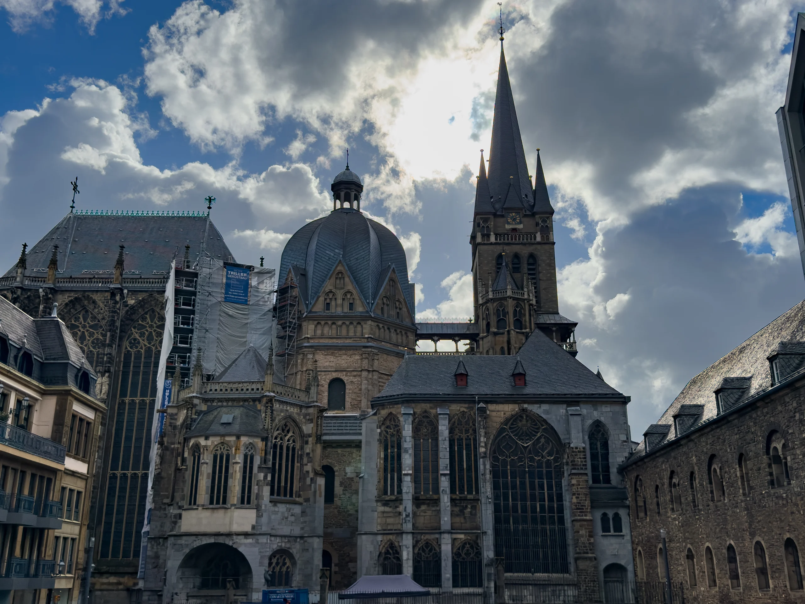 Aachen Cathedral with its Gothic tower and the dome of Charlemagne's palace chapel, part of the left side under scaffolding.